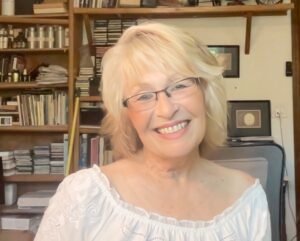 Misti Flowers, smiling, wearing a white top, sitting in her office